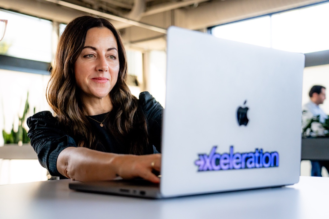 A team member working at a laptop with an Xceleration sticker