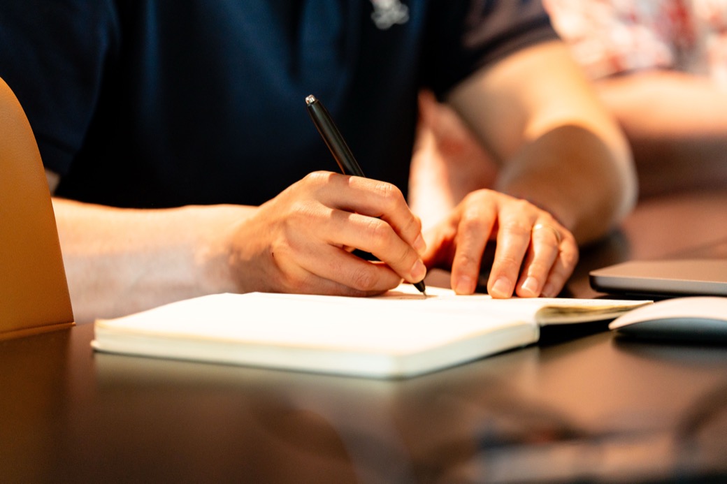 A hand writing figures in a notebook