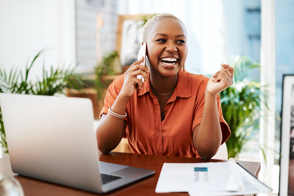 Smiling travel concierge on a phone call at her laptop