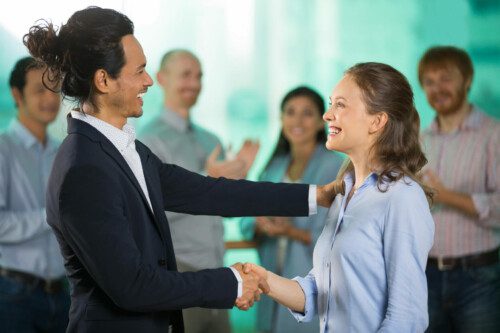 smiling business man congratulating colleague scaled